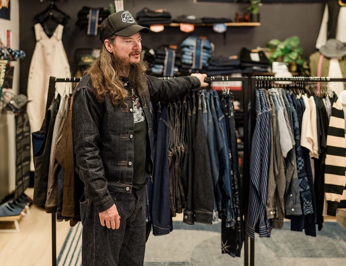 One of Oka's owners standing at the denim racks inside the shop